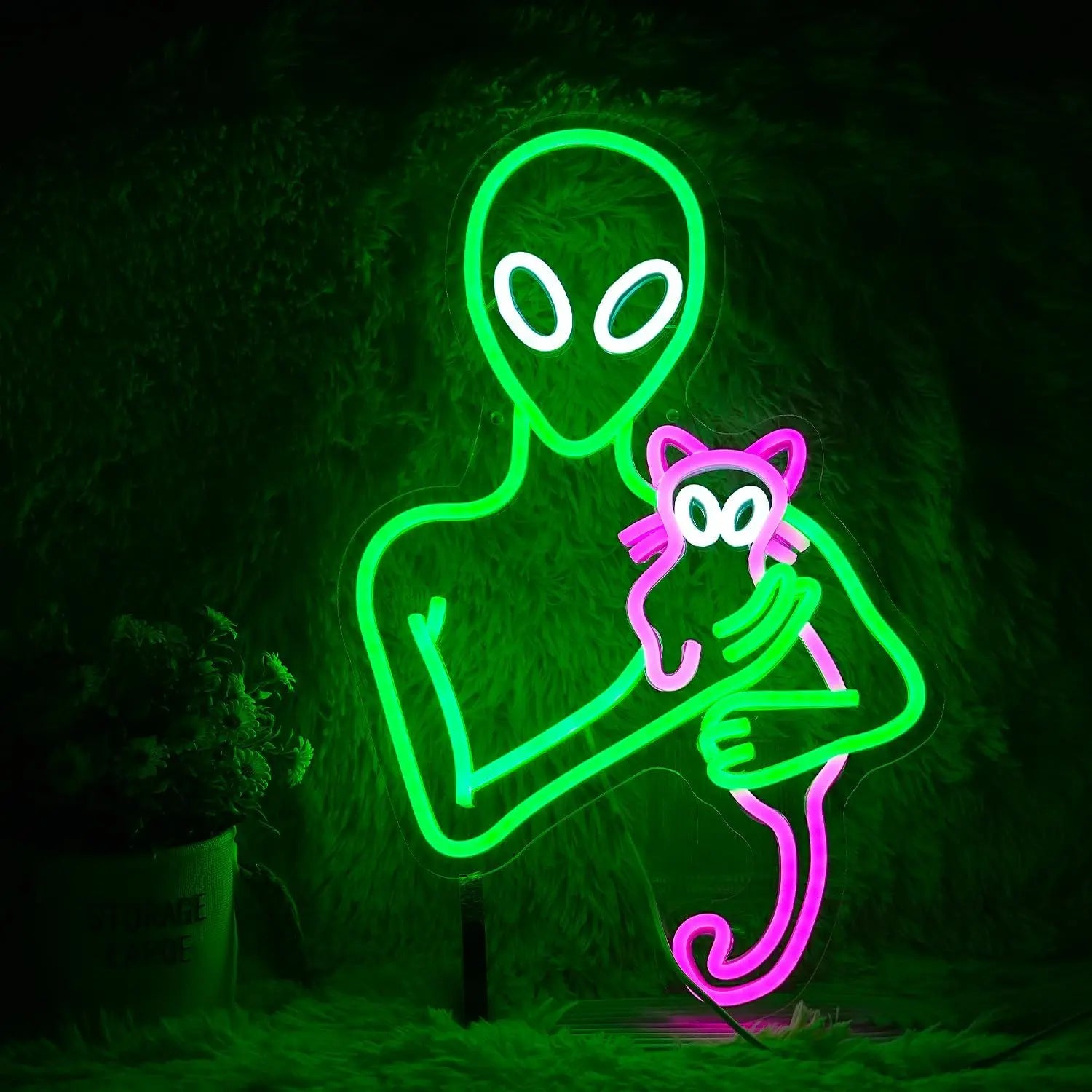 A glowing LED neon sign featuring a green alien holding a pink cat, perfect for adding a unique and quirky touch to your home decor.